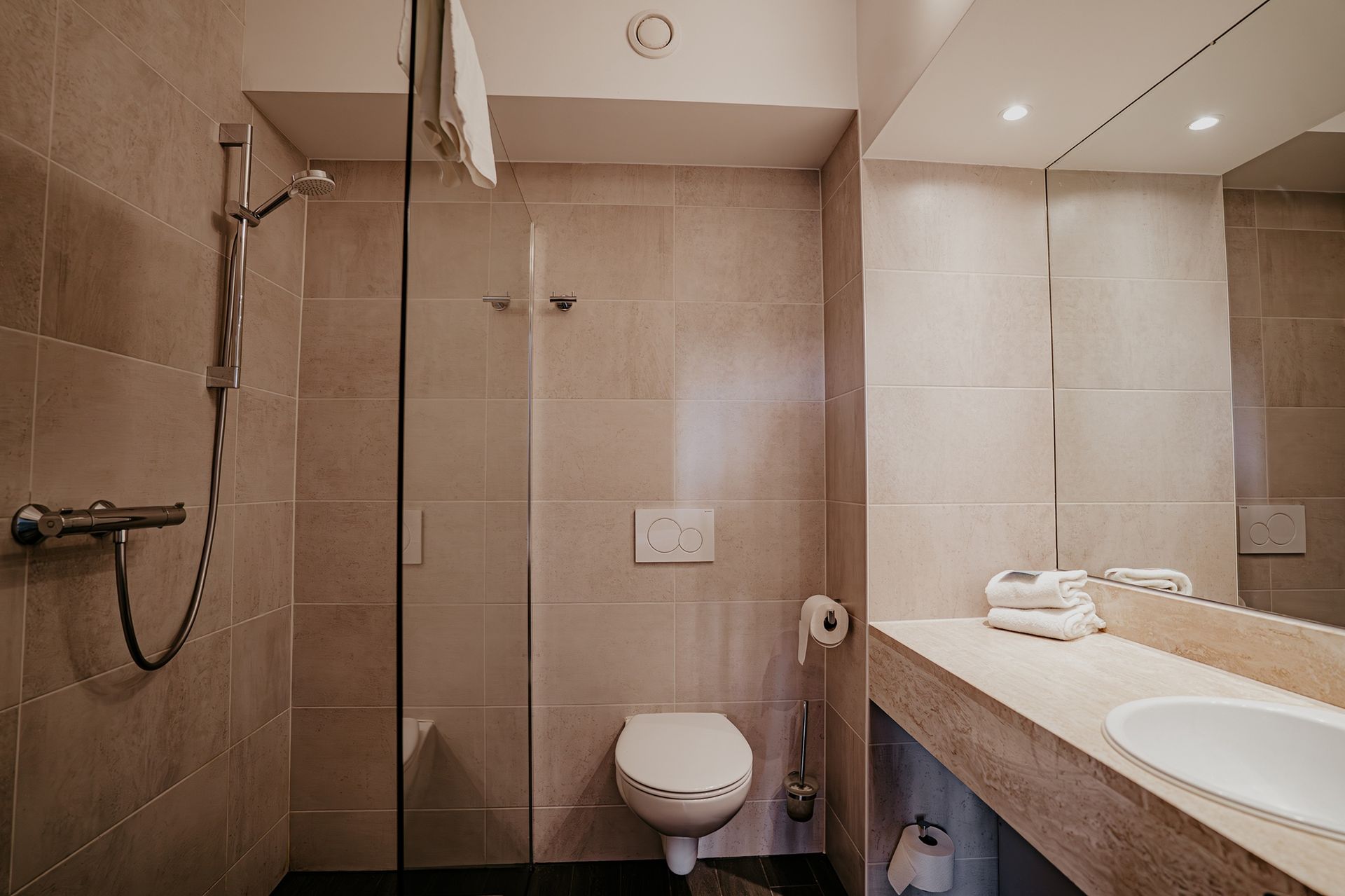 Badkamer van de standaard driepersoonskamer in Hotel Heemskerk met inloopdouche, toilet en wastafel.