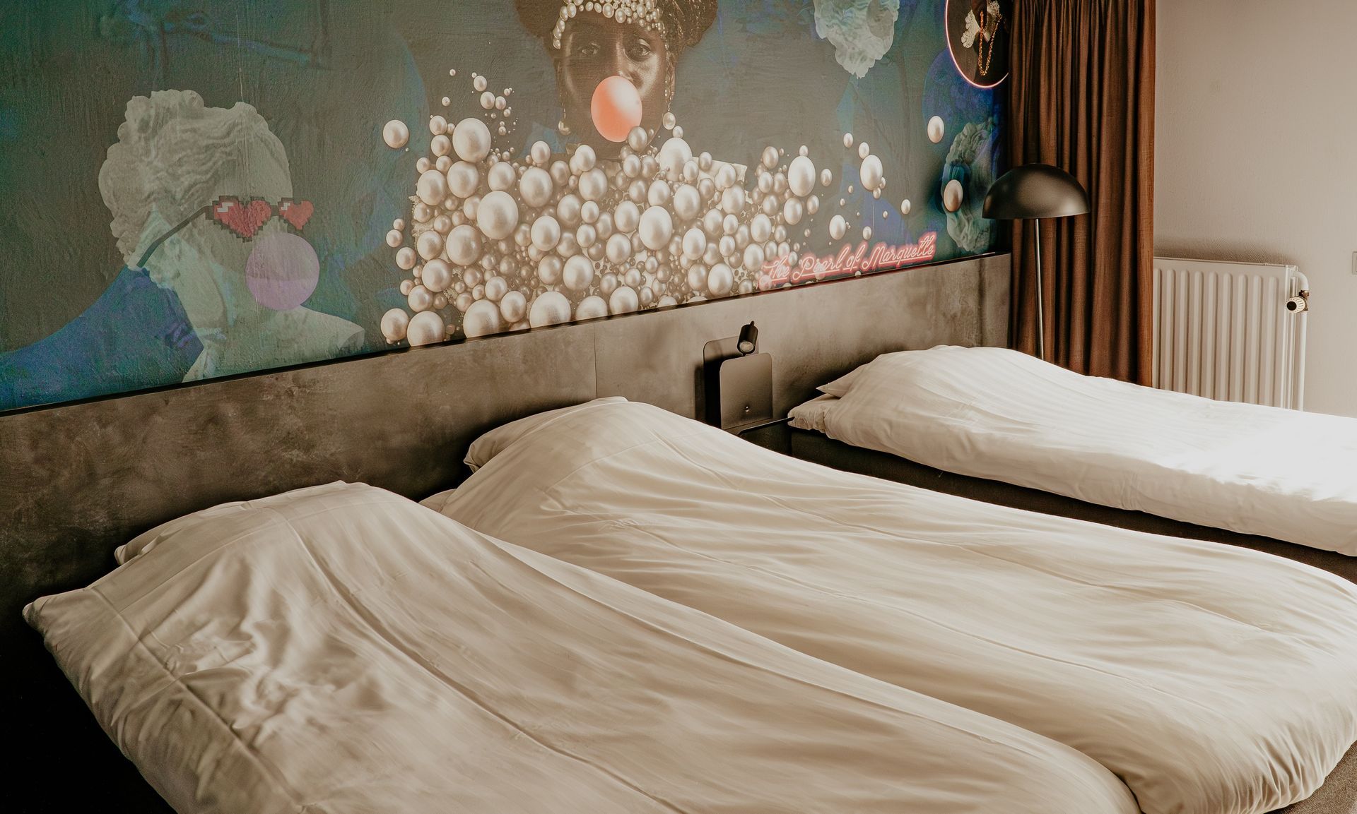 Standaard driepersoonskamer in Hotel Heemskerk met drie comfortabele bedden en kleurrijk decoratief behang met patronen boven het hoofdeinde.