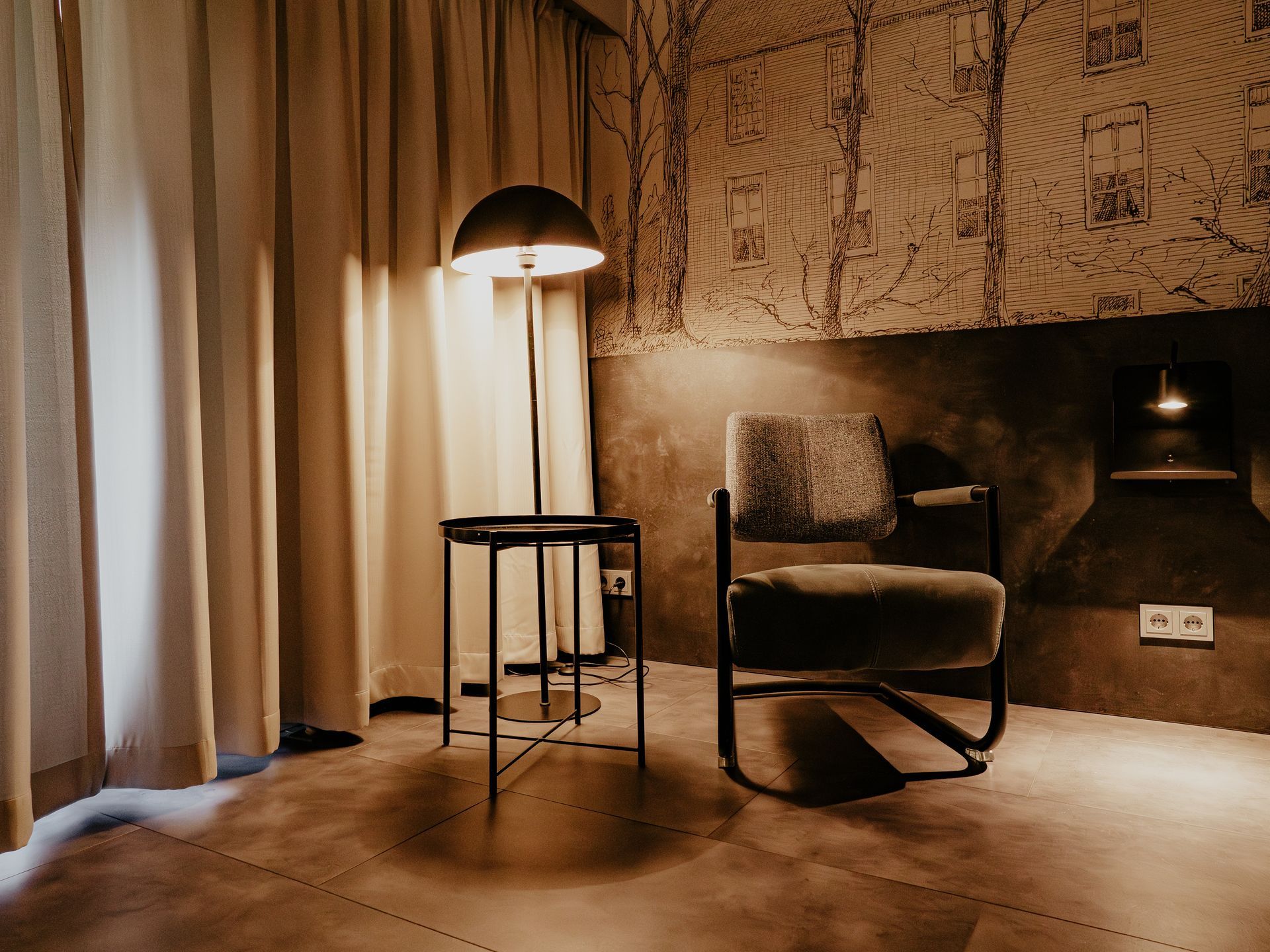 Comfort tweepersoonskamer in Hotel Heemskerk met sfeervolle zithoek, comfortabele stoel, lamp en decoratieve wand.