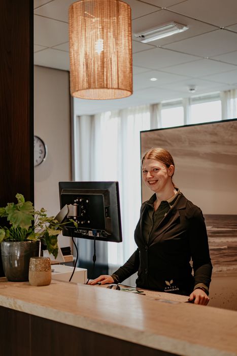 Een man zit te telefoneren bij de receptie van een hotel.