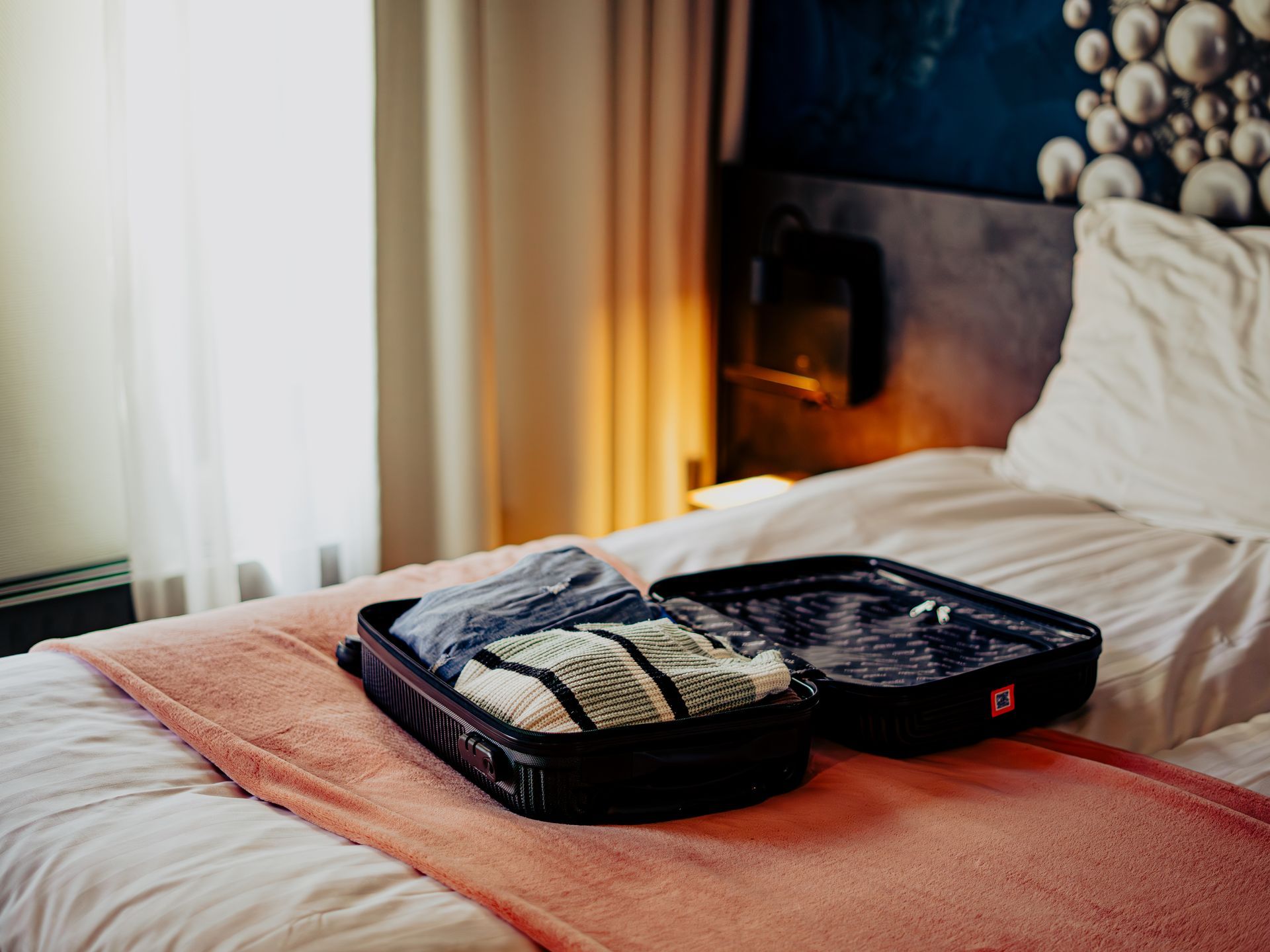 Standaard tweepersoonskamer in Hotel Heemskerk met opgemaakt bed en een open koffer met kleding.