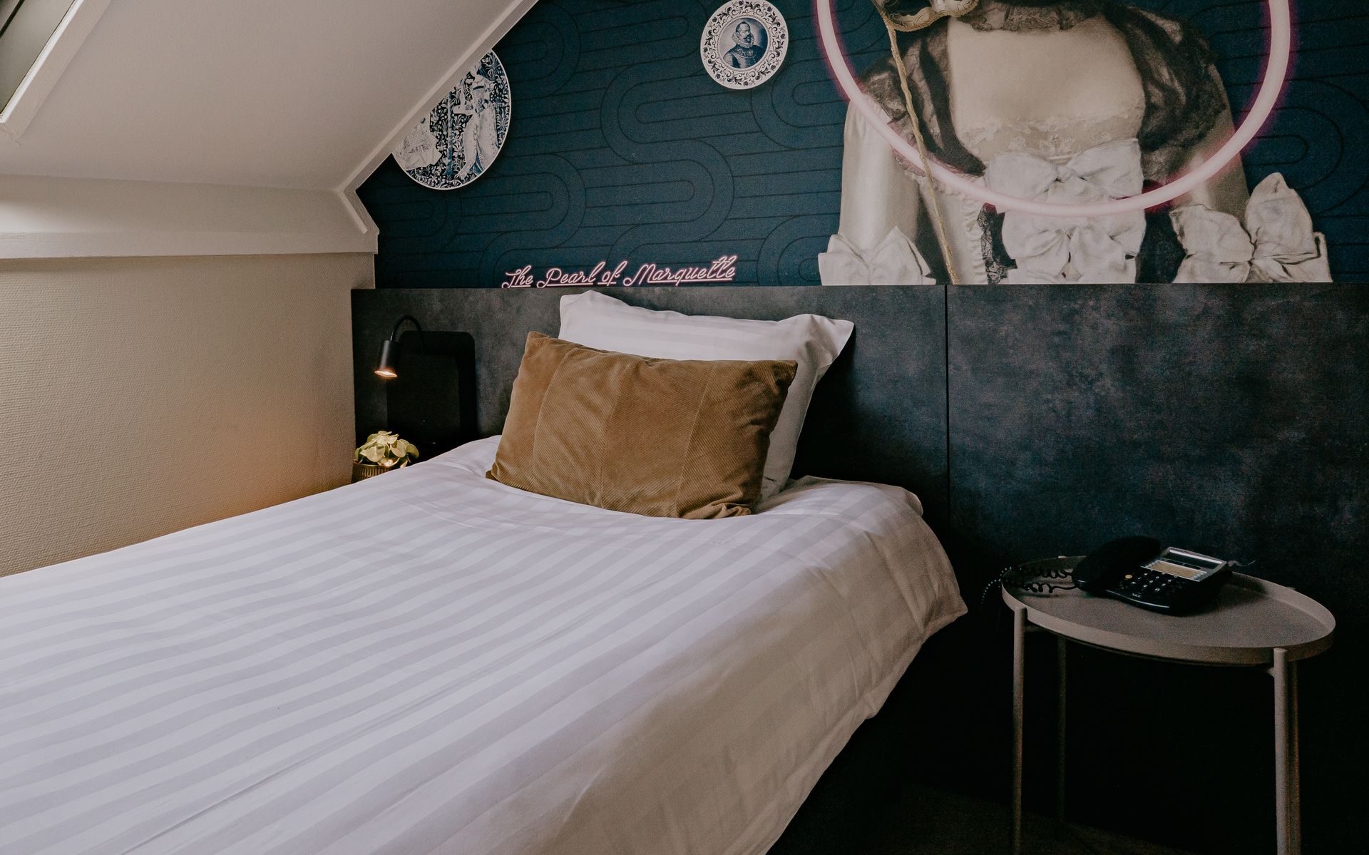 Een moderne eenpersoonskamer in Hotel Heemskerk met een comfortabel bed onder een schuin dak, een dakraam dat uitzicht biedt op groen, een bureau met stoel en een kleine tafel met een koffiezetapparaat.