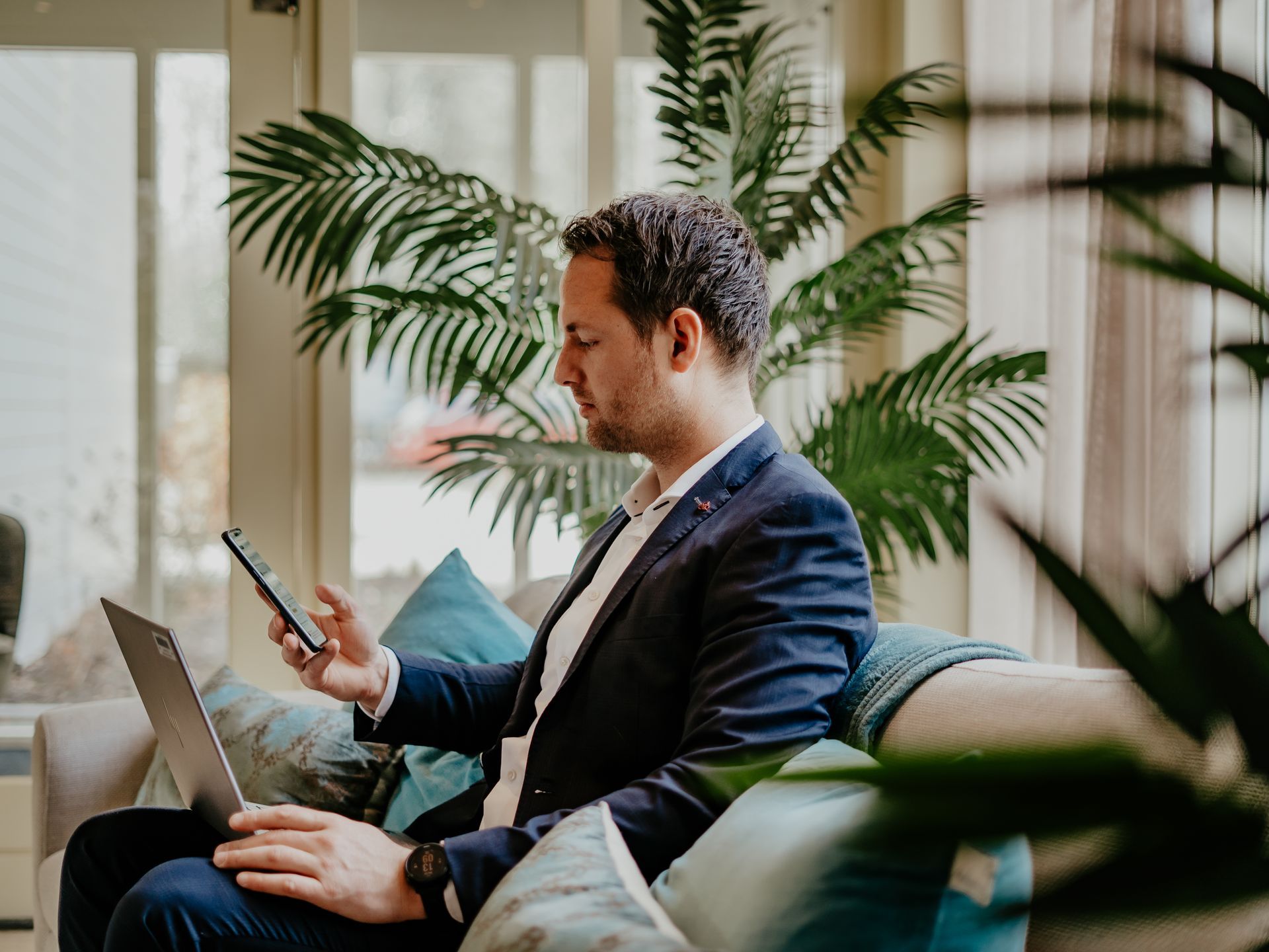 Een laptop, een kop koffie, een mobiele telefoon en een luidspreker staan ​​op een houten tafel.