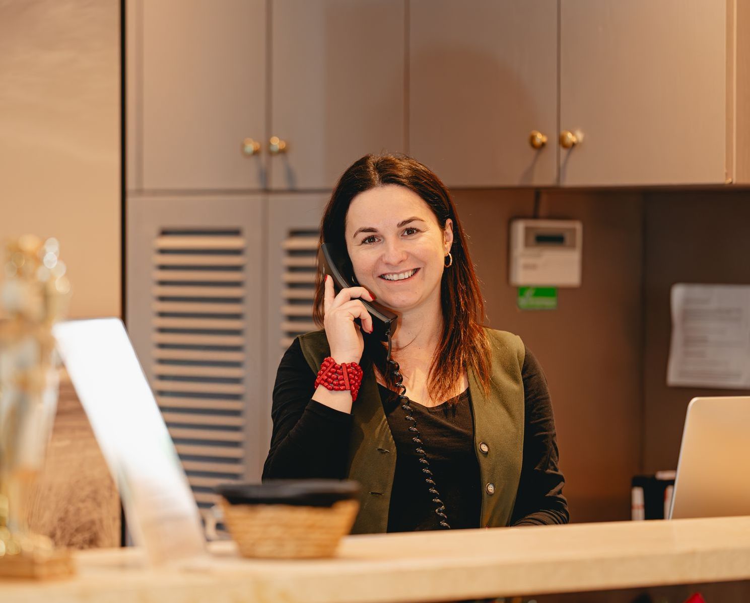 Een vrouw staat te telefoneren bij de receptie van een hotel.