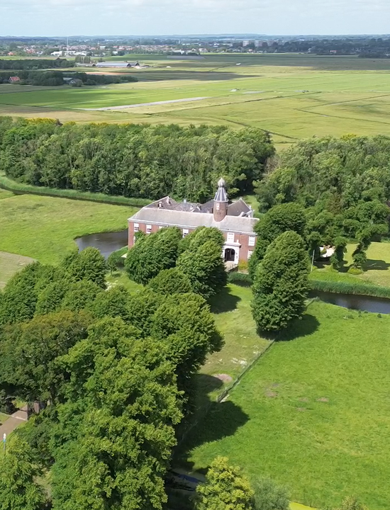 Een luchtfoto van Kasteel Marquette in Heemskerk, Noord-Holland. Het kasteel is omringd door een gracht, uitgestrekte groene velden en bosrijk gebied.