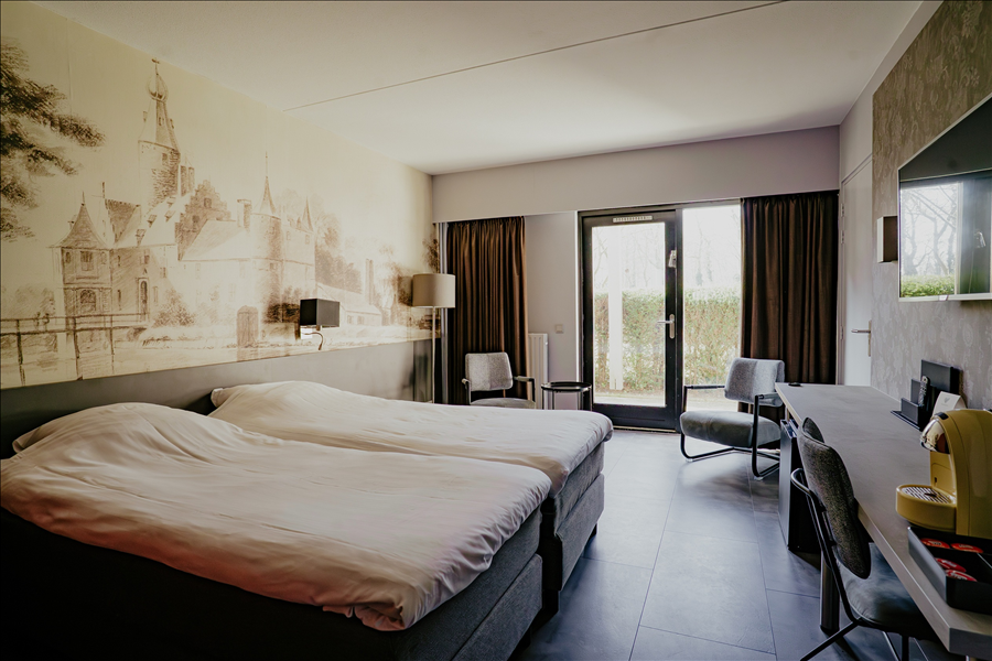 Luxury suite at Hotel Heemskerk with ensuite bathroom, modern wooden wall paneling with vertical lines, a stylishly made bed with decorative pillows, and a view into a spacious bathroom with a large standing mirror and wall art.