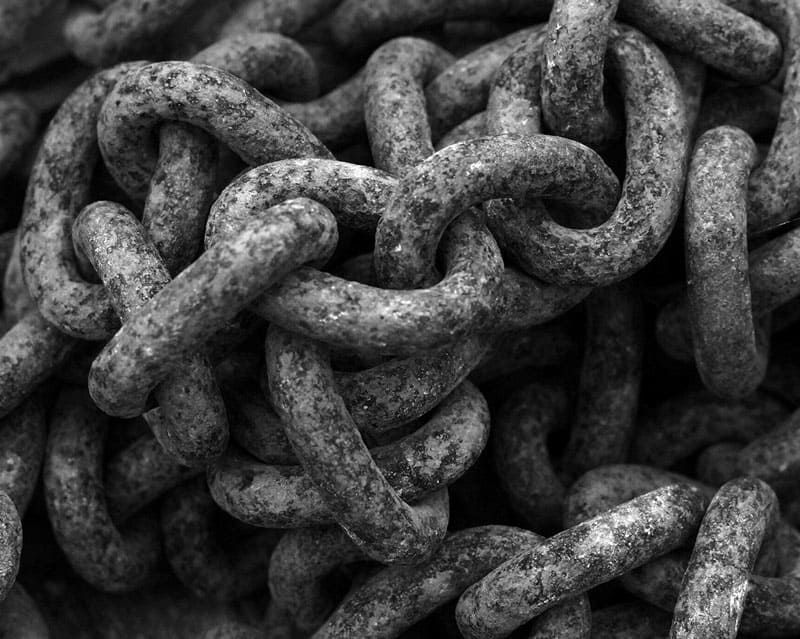 Una fotografía en blanco y negro de una pila de cadenas oxidadas.