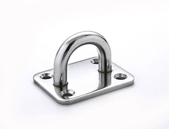 Un gancho de acero inoxidable reposa sobre una superficie blanca.