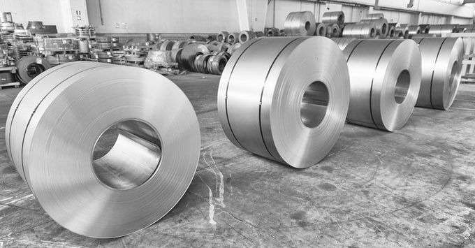 Una fotografía en blanco y negro de rollos de acero inoxidable en una fábrica.
