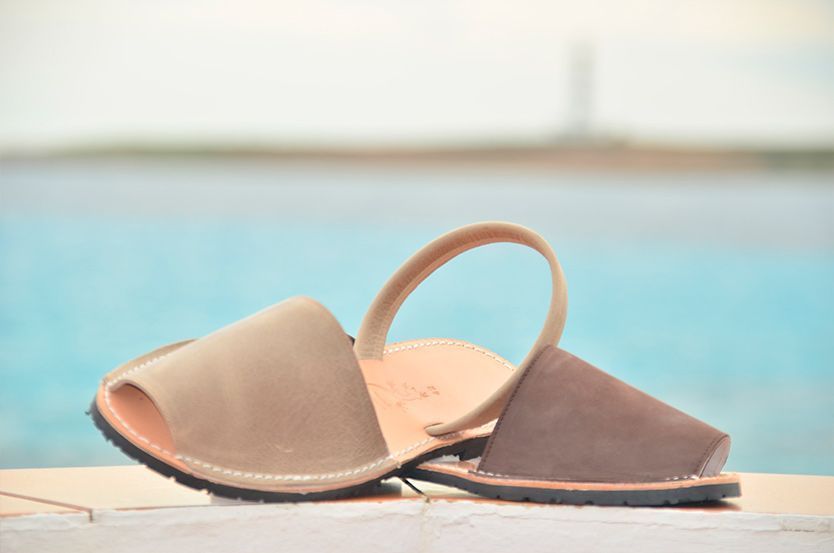 A pair of sandals are sitting on a ledge near the water.