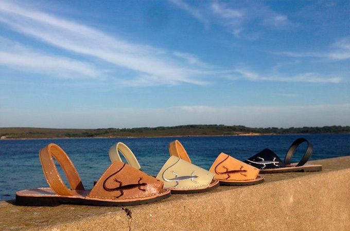 Tres pares de sandalias están alineadas en una pared cerca del océano.