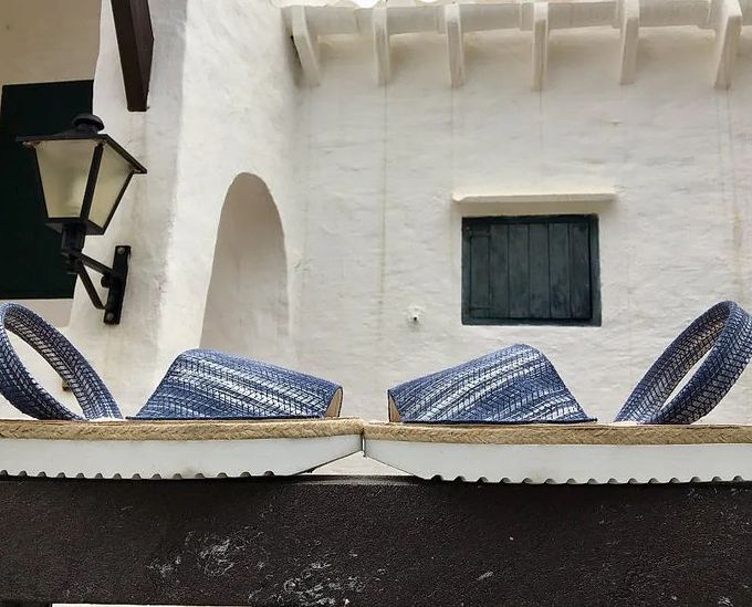 Un par de sandalias están sobre una repisa frente a un edificio blanco.