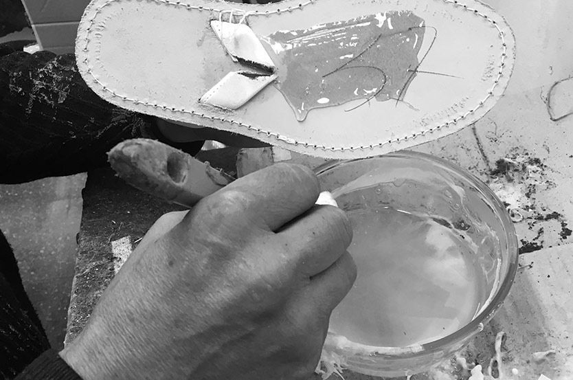 A black and white photo of a person making a shoe