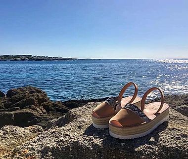 A pair of sandals are sitting on a rock near the ocean.