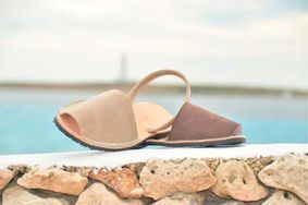 A pair of sandals sitting on top of a rock wall next to a body of water.