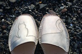 A pair of shoes with a cat on them are sitting on a pile of rocks.