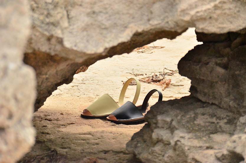 A pair of sandals are sitting in a cave on the beach.
