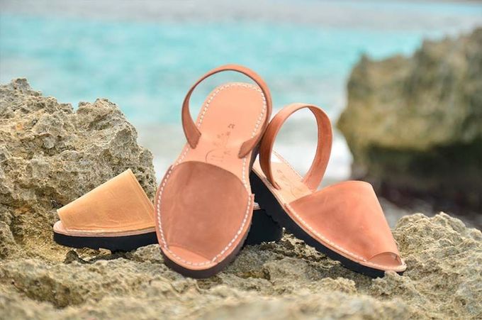 Un par de sandalias colocadas encima de una roca cerca del océano.
