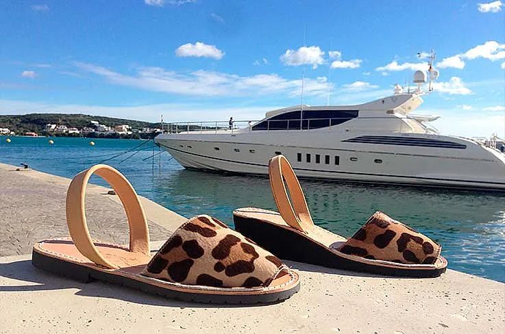 A pair of leopard print sandals are sitting on a dock next to a boat.