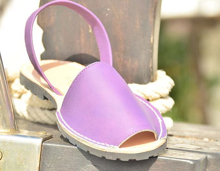 A pair of purple sandals are sitting on a wooden block