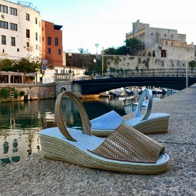 A pair of sandals are sitting on the ground in front of a bridge over a body of water