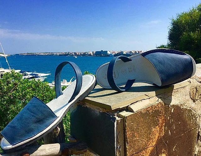 A pair of blue sandals are sitting on top of a stone wall.