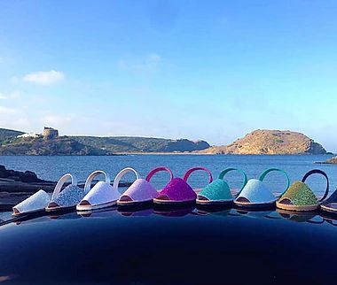 A row of colorful sandals are sitting on top of a car near the ocean.