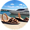 A pair of sandals are sitting on a dock next to a boat.