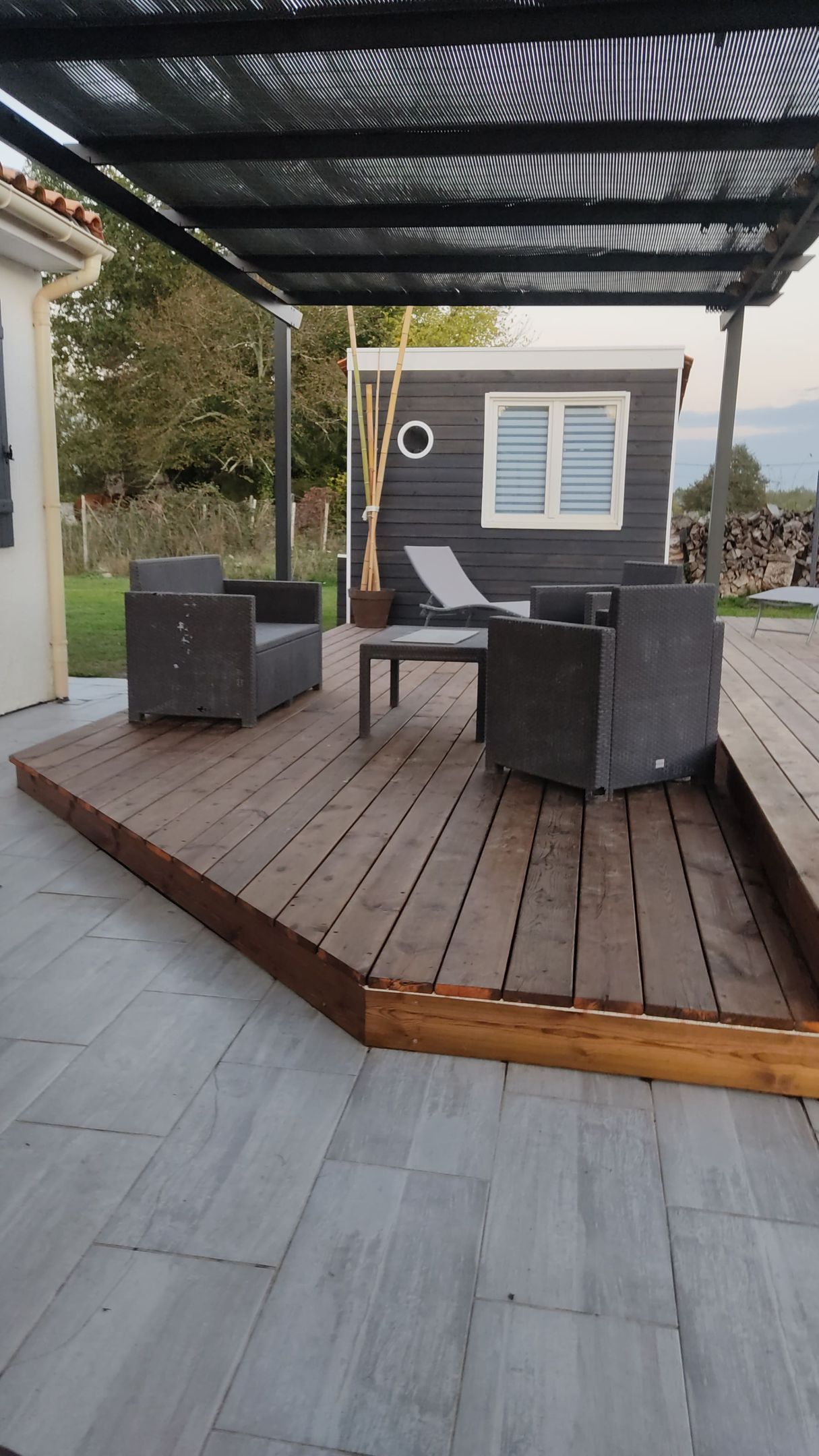 Une terrasse en bois avec un salon de jardin avec de gros fauteuil