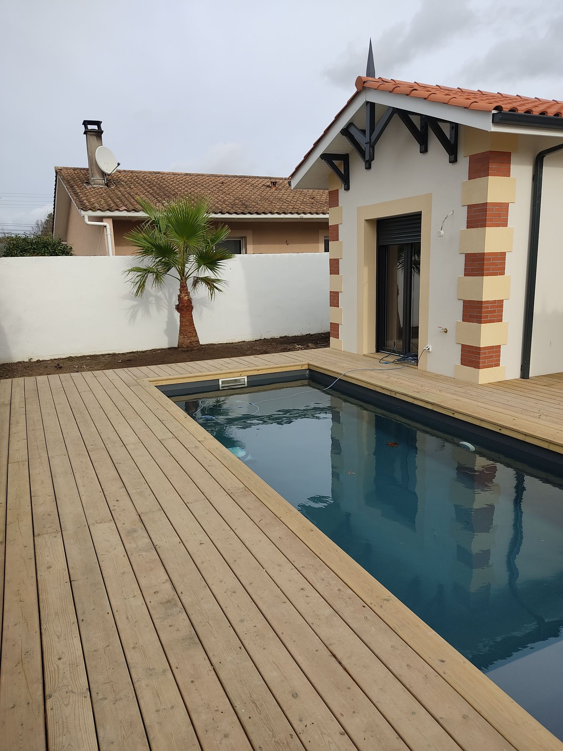 Une piscine enterrée avec une terrasse en bois qui l'entoure