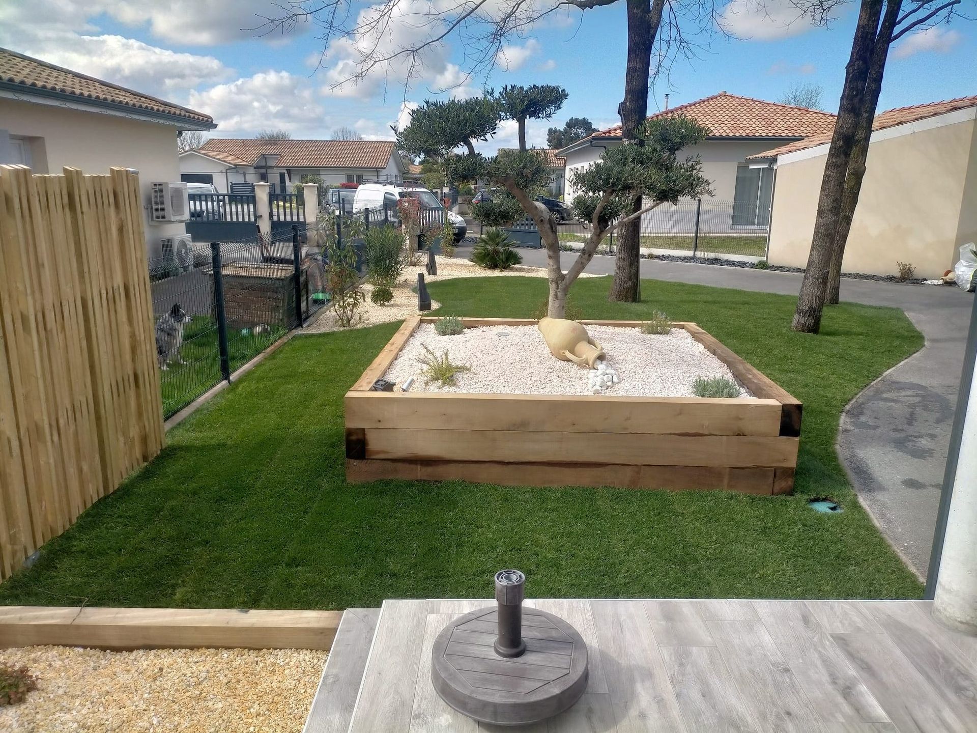 Un arbre dans une jardinière avec une amphore et du gravier blanc