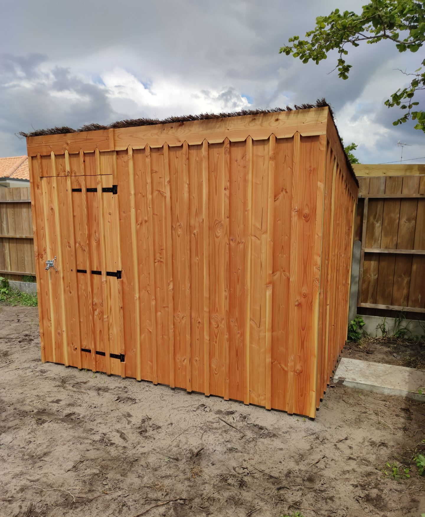 Un abri en bois avec une barrière en bois derrière