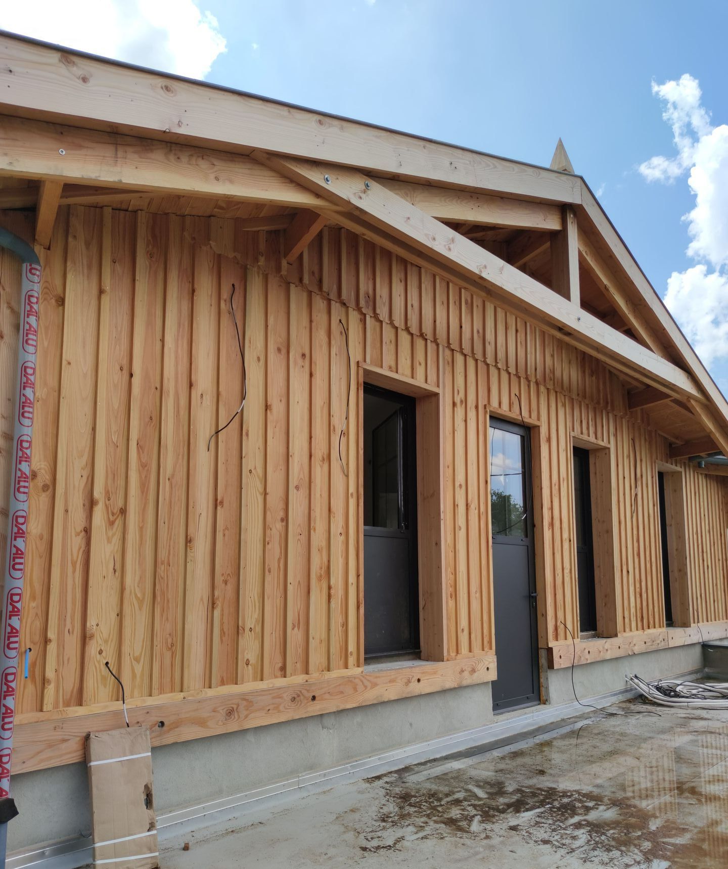 Une maison couverte de bardage en bois avec des portes vitrées noires