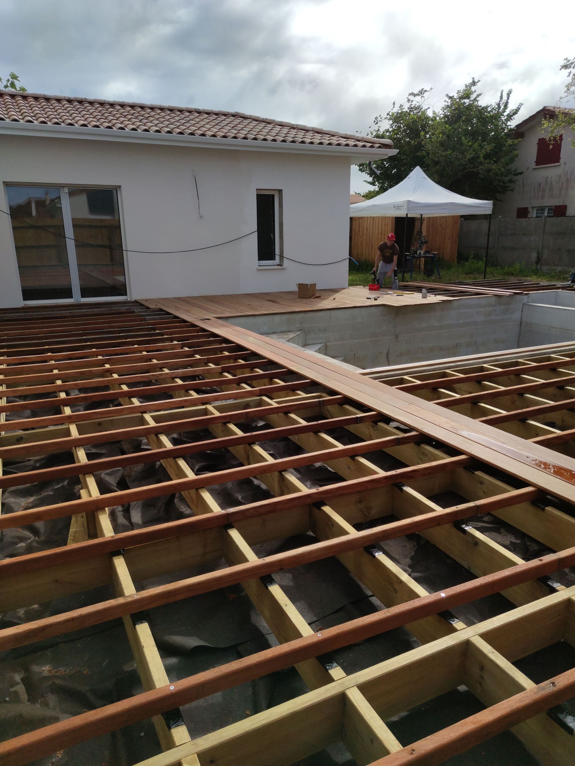 Une terrasse en bois en cours de fabrication avec une piscine creusée aussi en cours de construction