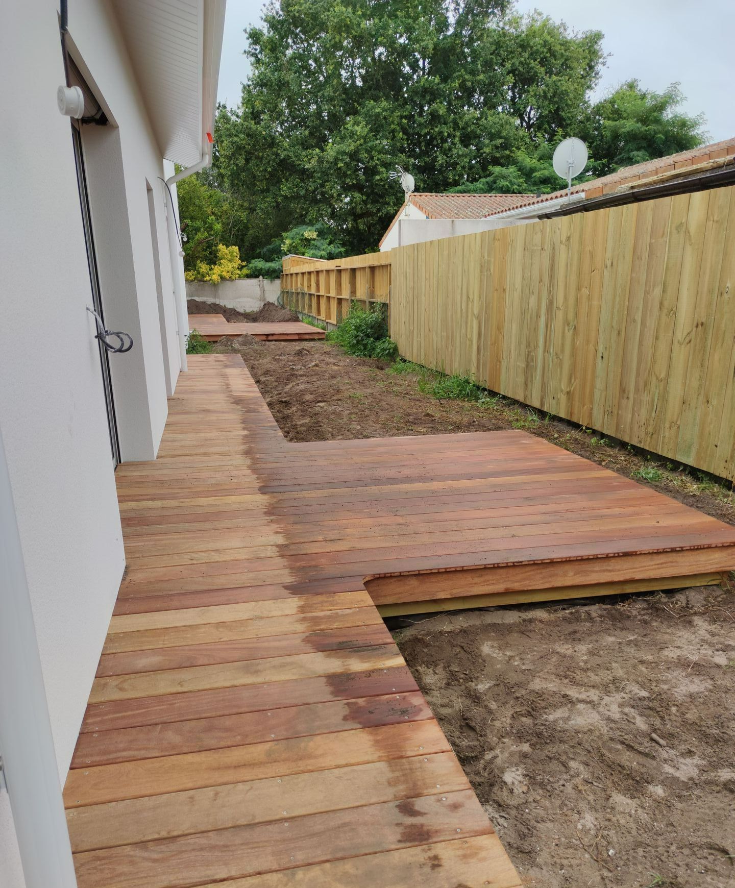 Une terrasse en bois à côté d'une clôture en bois