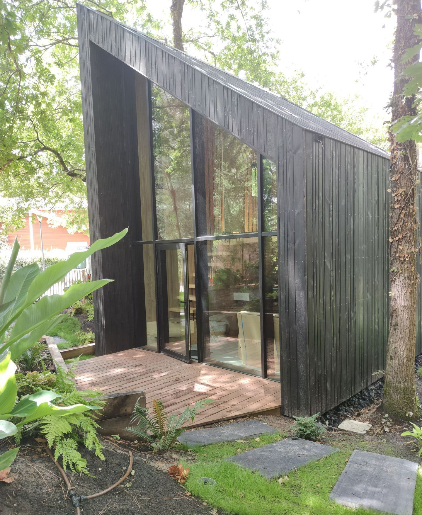 Une terrasse devant une maison en bois avec une grande baie vitrée
