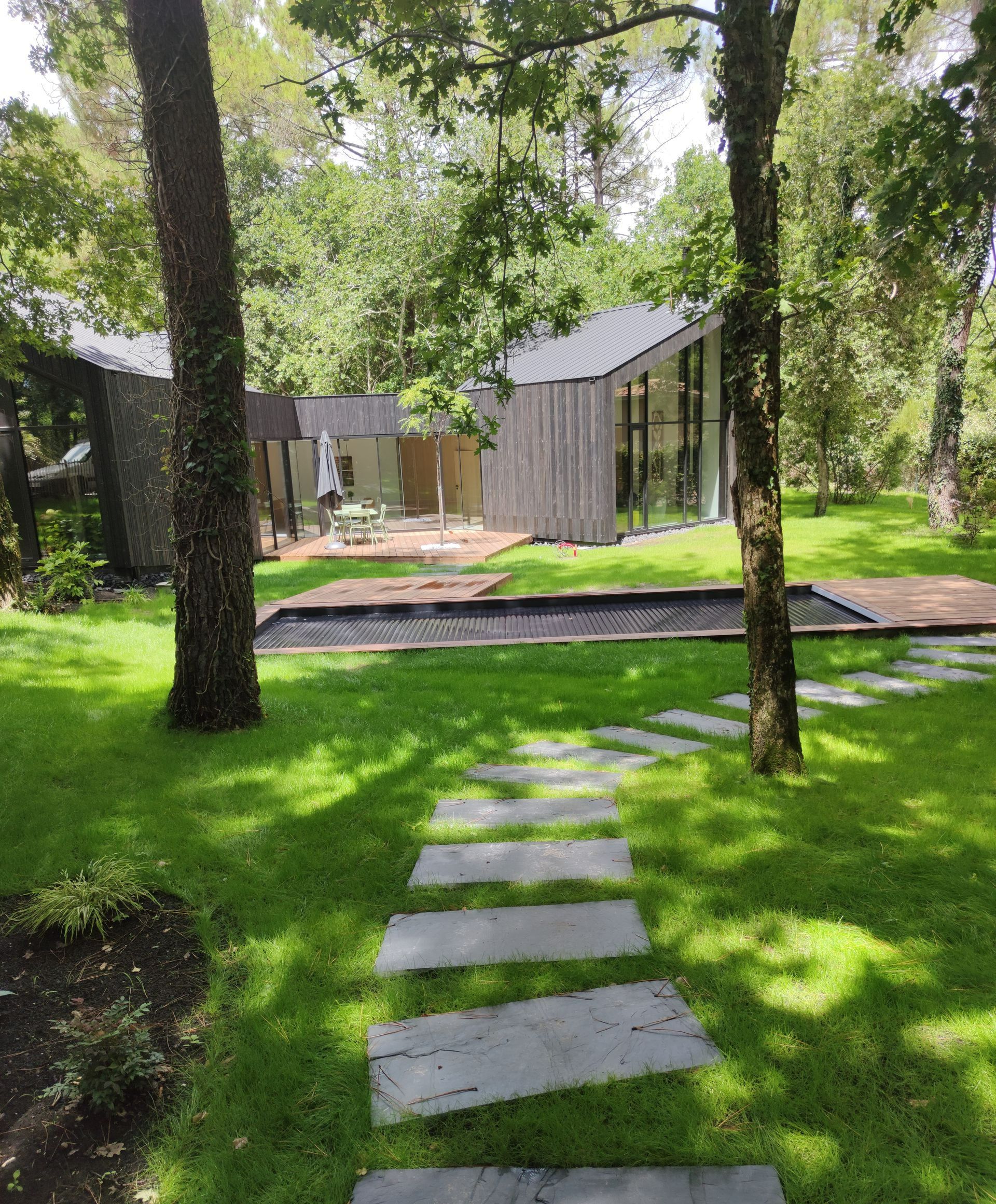 Un jardin traversé par un chemin de pierres et avec des arbres