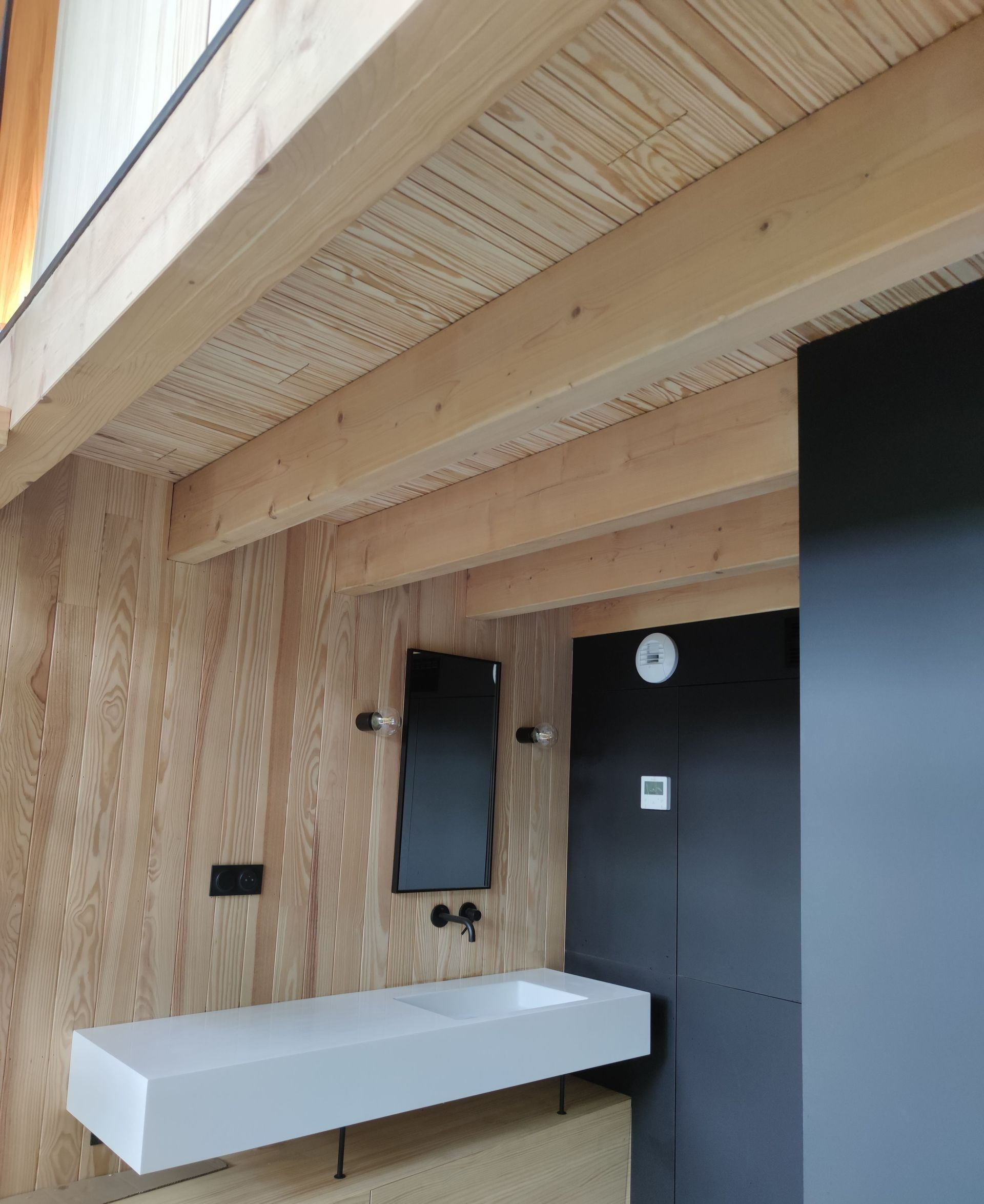 Un espace d'eau avec les murs couverts par des planches en bois et un mur noir