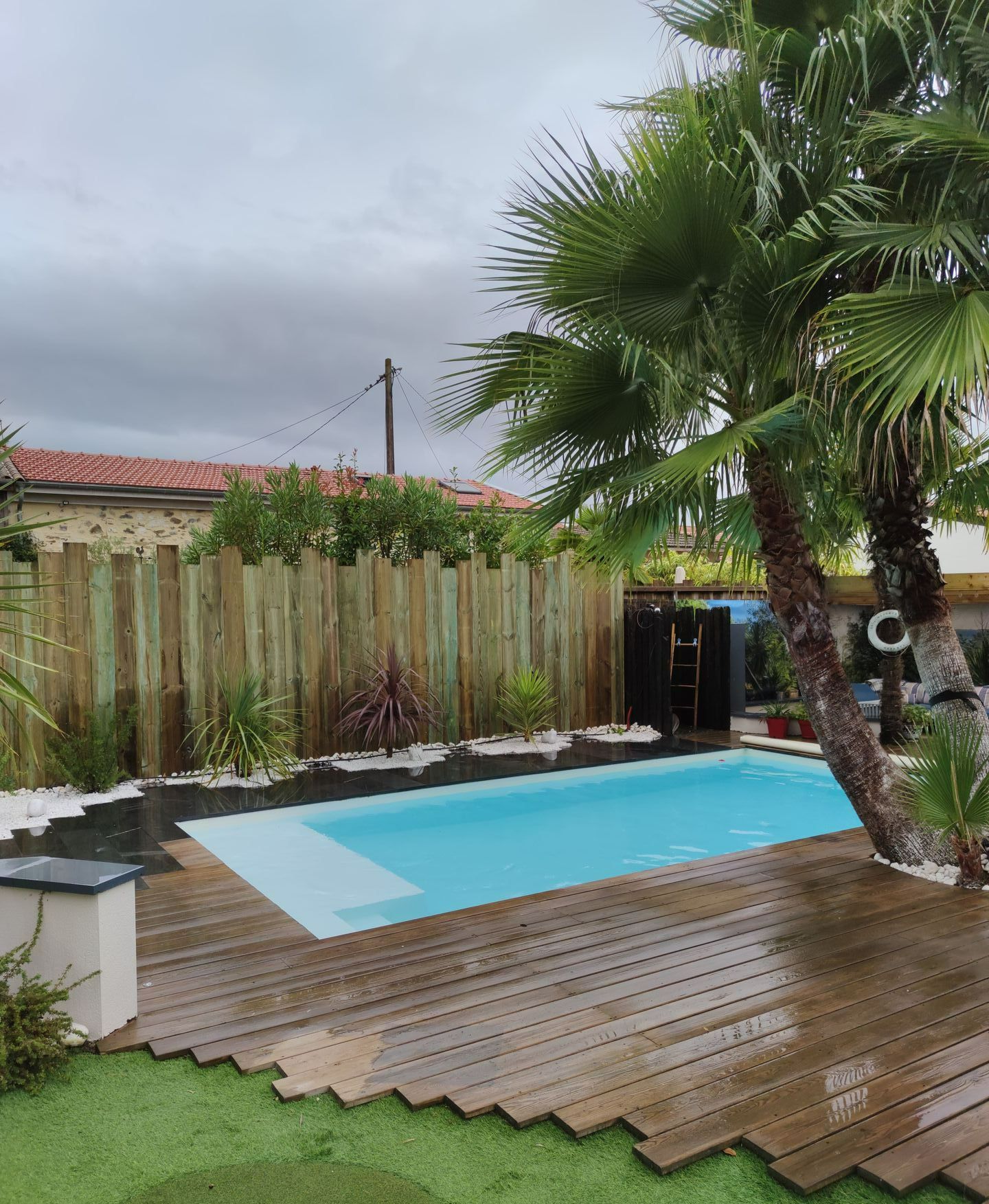 Une piscine avec des palmiers et du gravier noir