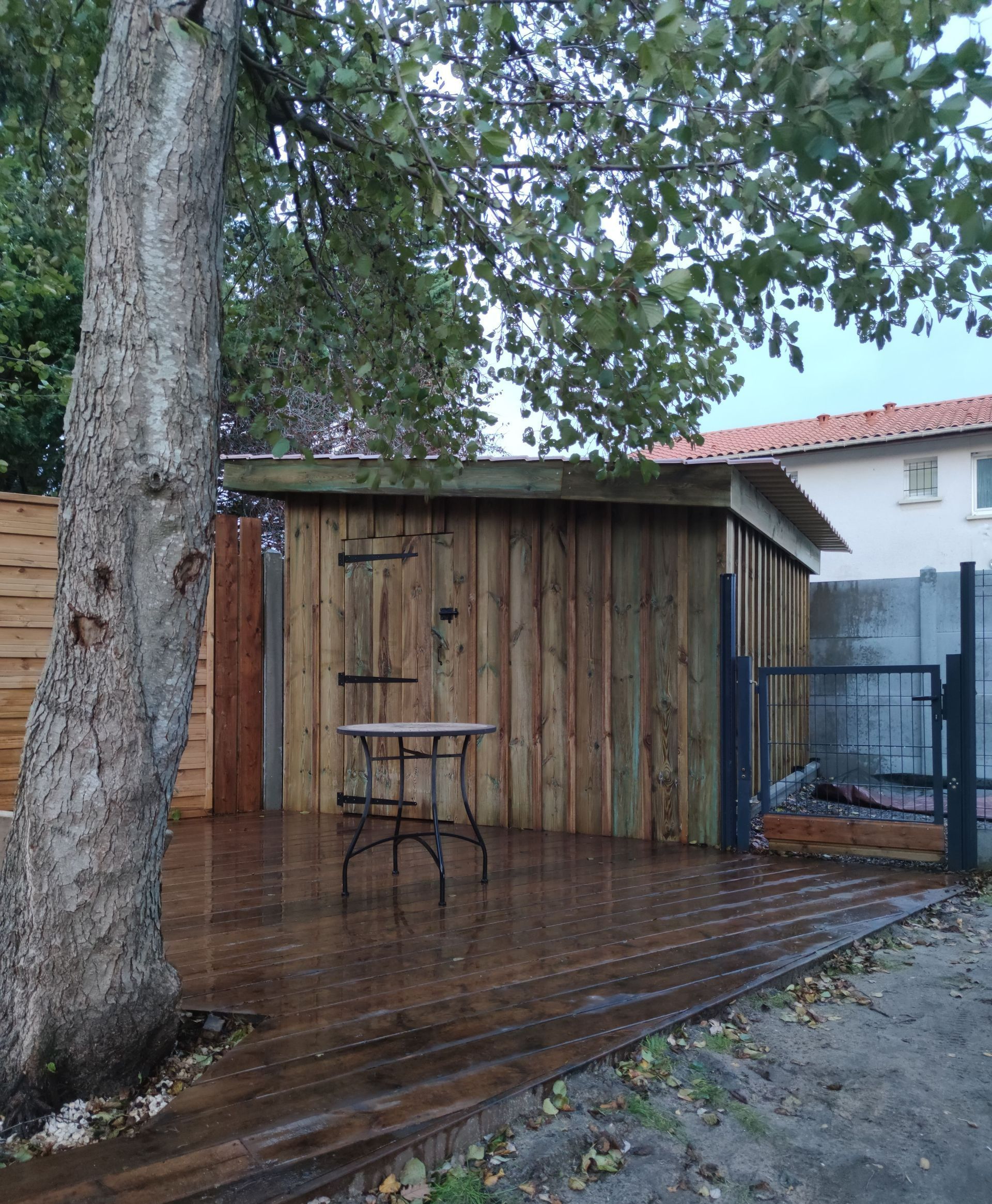Un abri en bois avec une table et un arbre d'avant