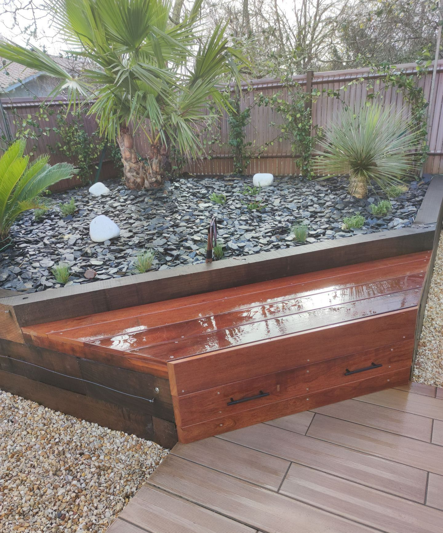 Un coffre en bois avec une jardinière avec des graviers noirs