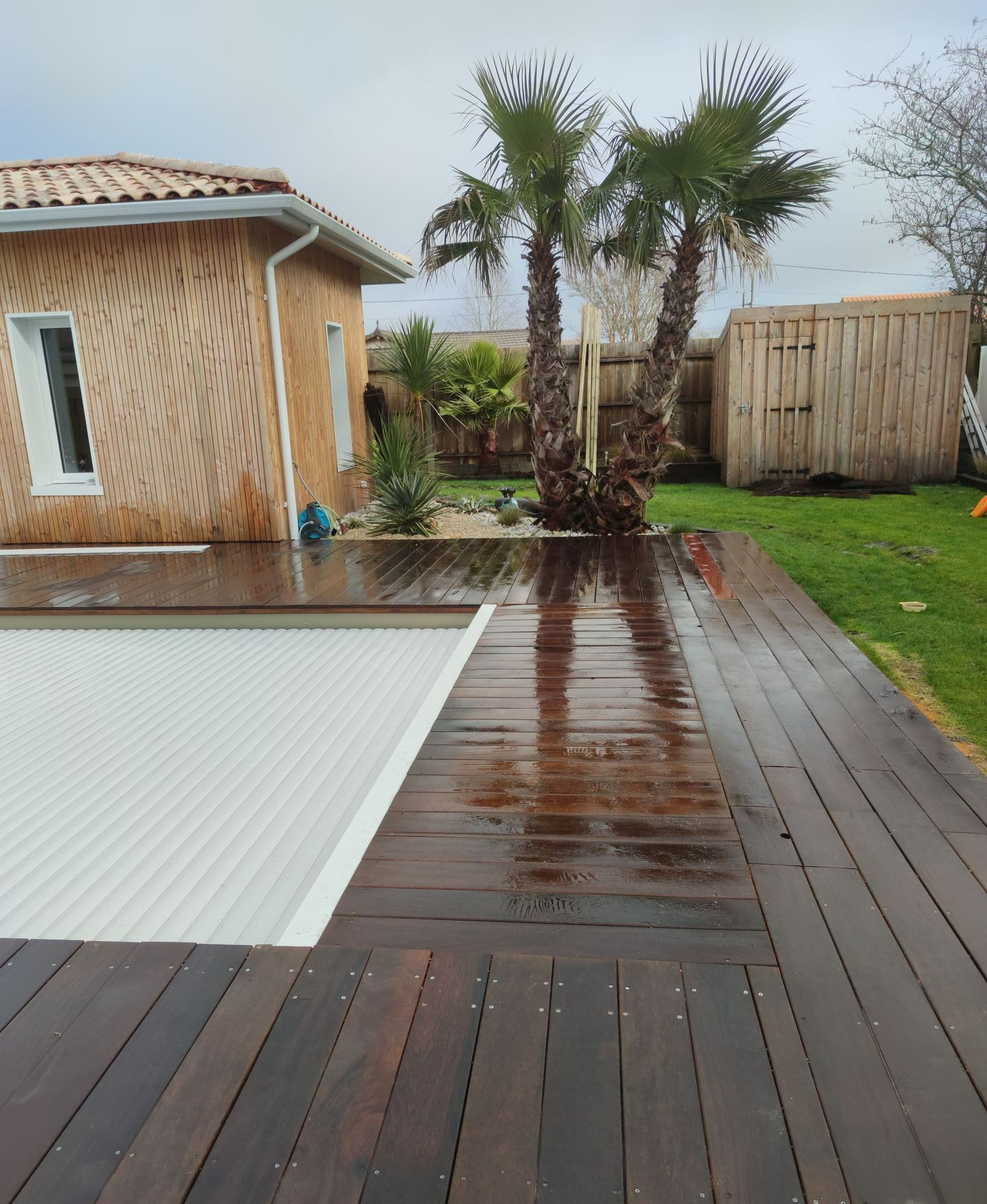 Une terrasse en bois autour d'une piscine qui est couverte