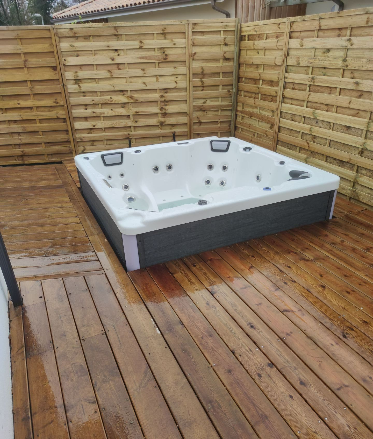 Un jacuzzi entouré par une terrasse en bois