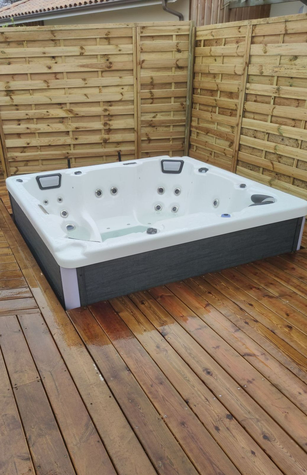 Un jacuzzi sur une terrasse en bois et entouré par une clôture en bois