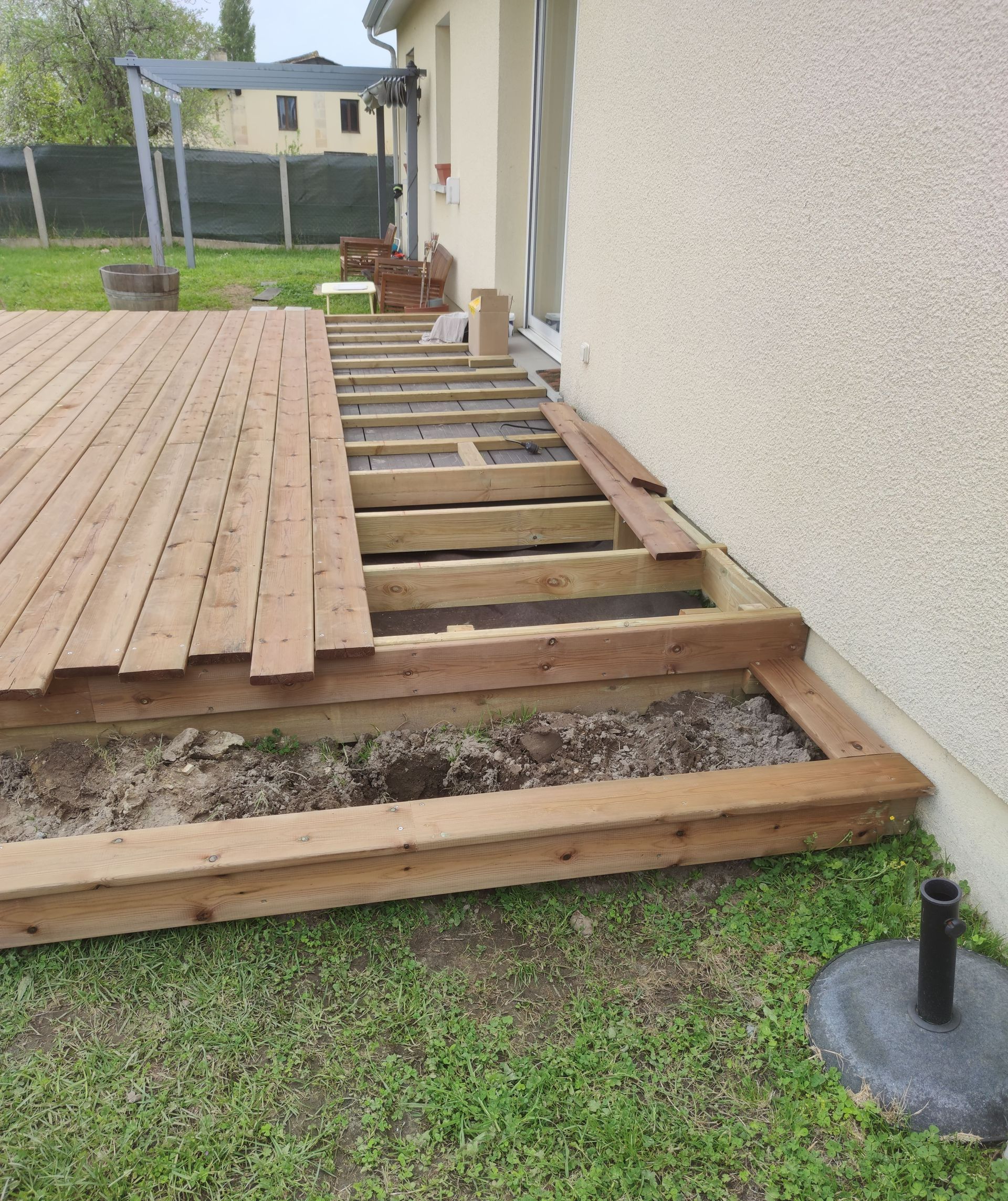 Terrasse en bois en construction avec un mur blanc sur le côté droit