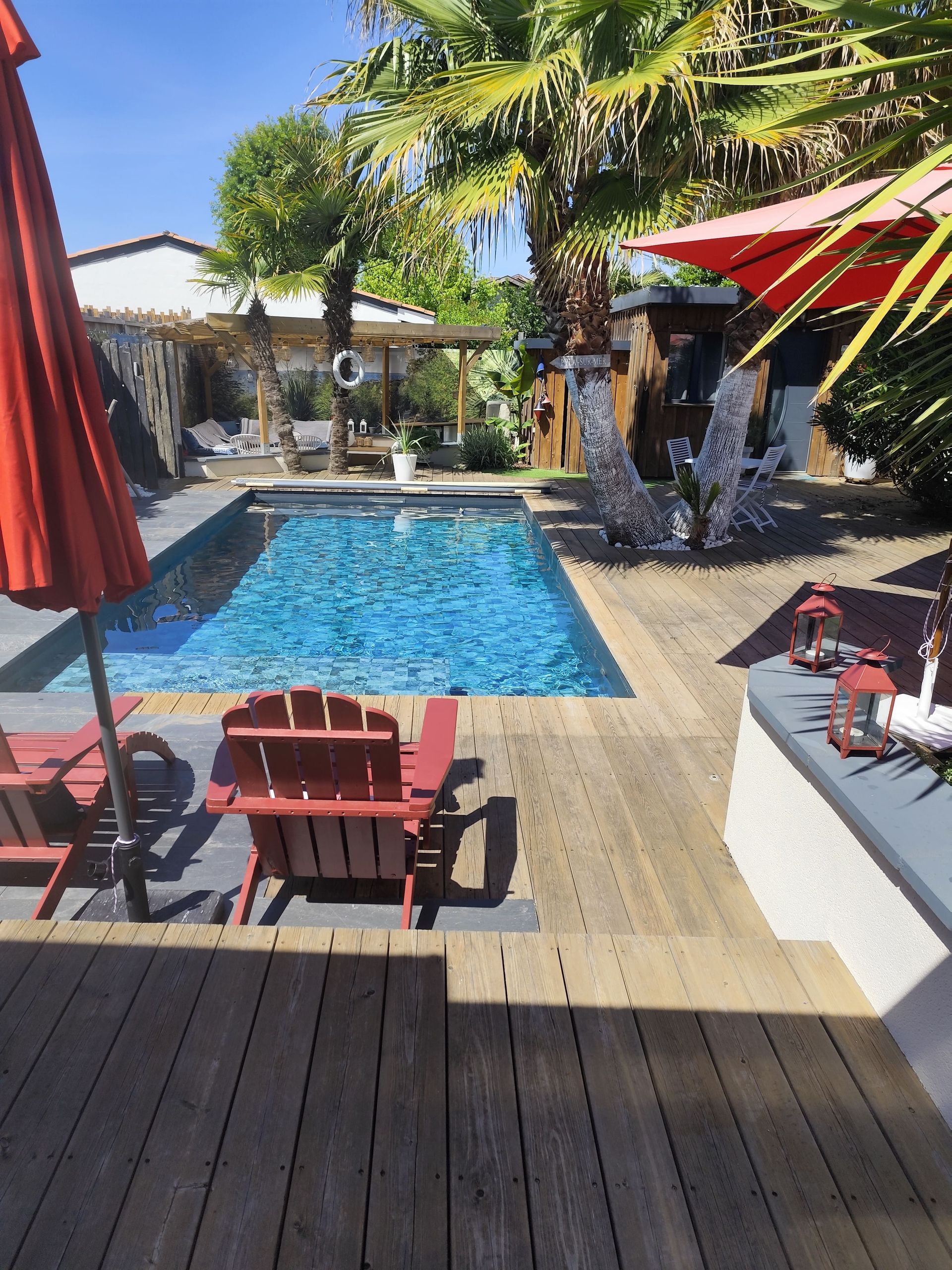 Une piscine avec des chaises longues rouges sur le côté et une terrasse en bois