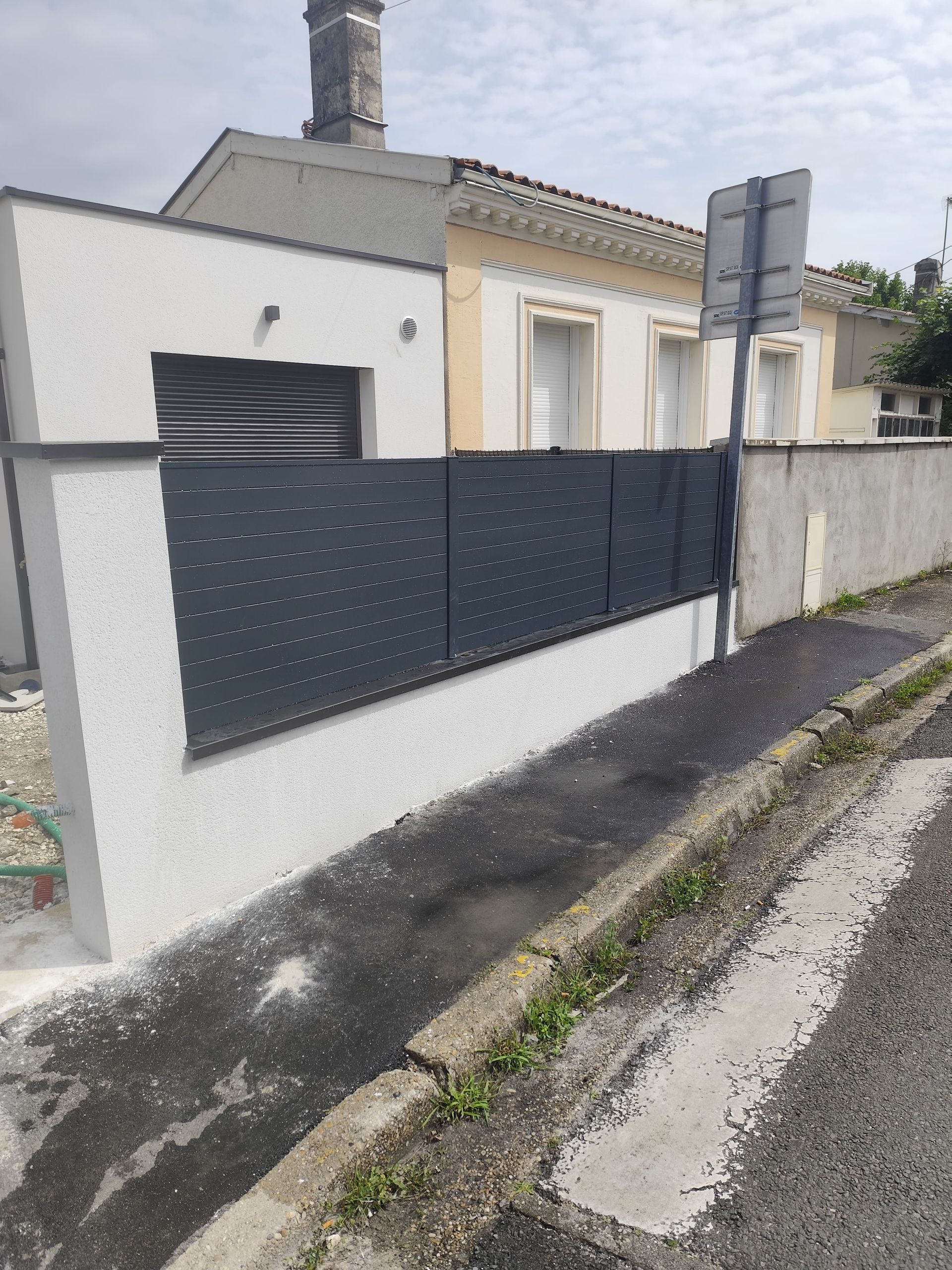 Une barrière grise sur un muret blanc