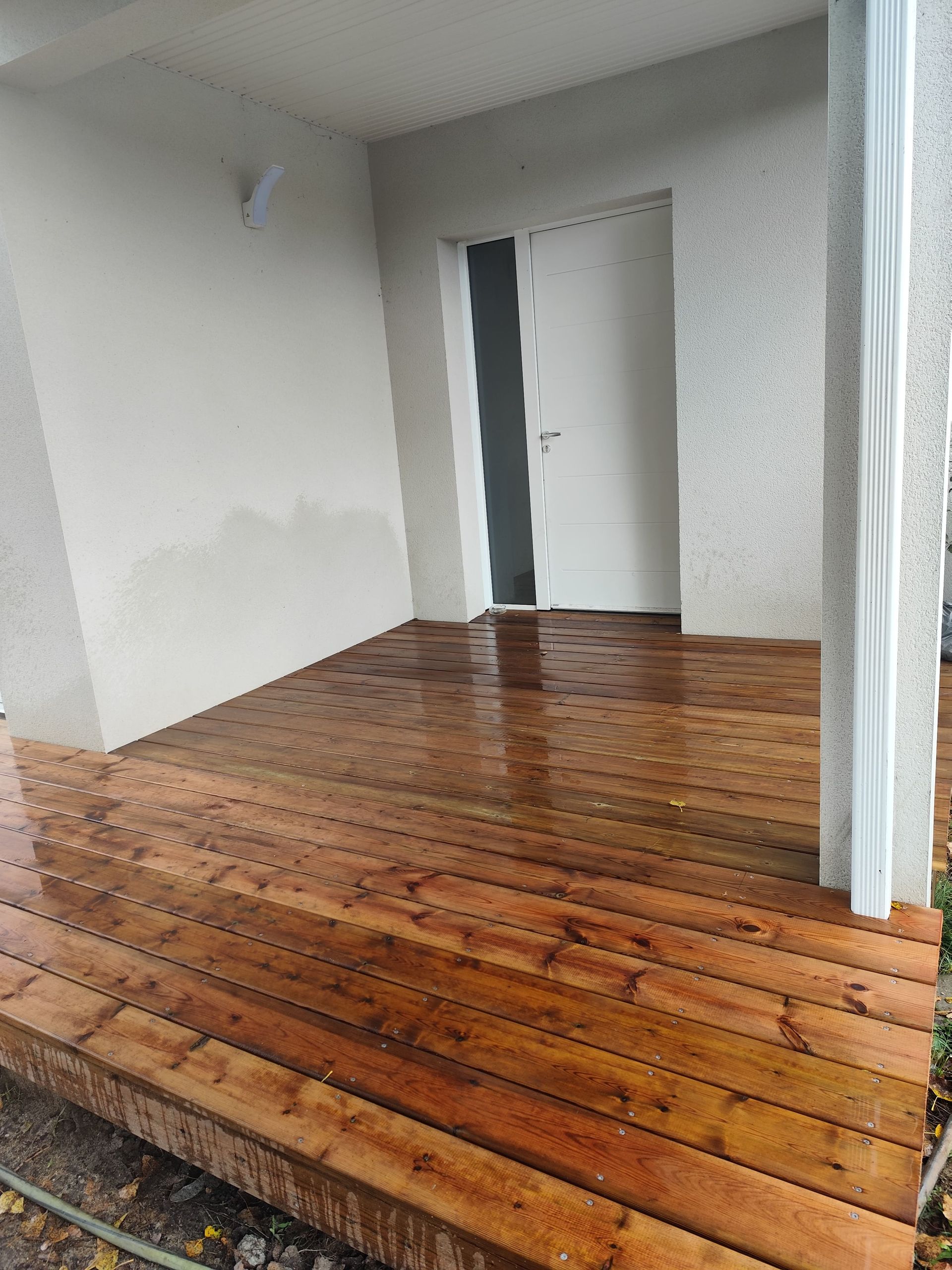 Entrée avec une terrasse en bois et des murs blancs