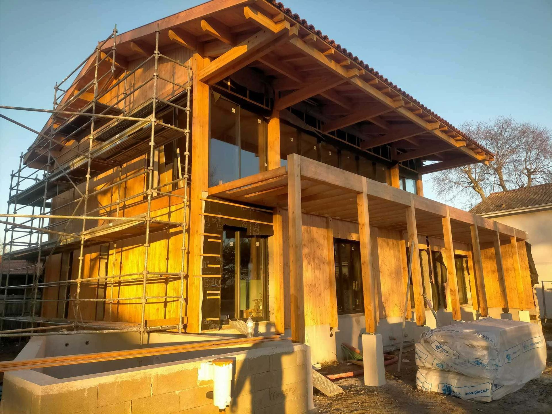 Une maison avec un échafaudage pour mettre en place un bardage en bois.