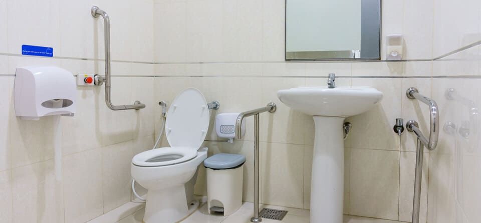 Salle de bain PMR avec toilette et point d'eau.